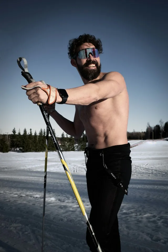Cross-country skier with sunglasses and ski poles on a snowy trail